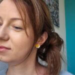 cercei din lut polimeric, buchet cu 3 flori in nuante de galben si crem purtati de o femeie. cerceii sunt pe lobul urechii