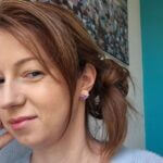 cercei din lut polimeric, buchet cu 3 flori in nuante de violet si crem purtati de o femeie. cerceii sunt pe lobul urechii