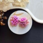 Cercei din lut polimeric, buchet cu 3 flori in nuante de roz asezati pe un suport ceramic. Se pot observa detaliile florilor