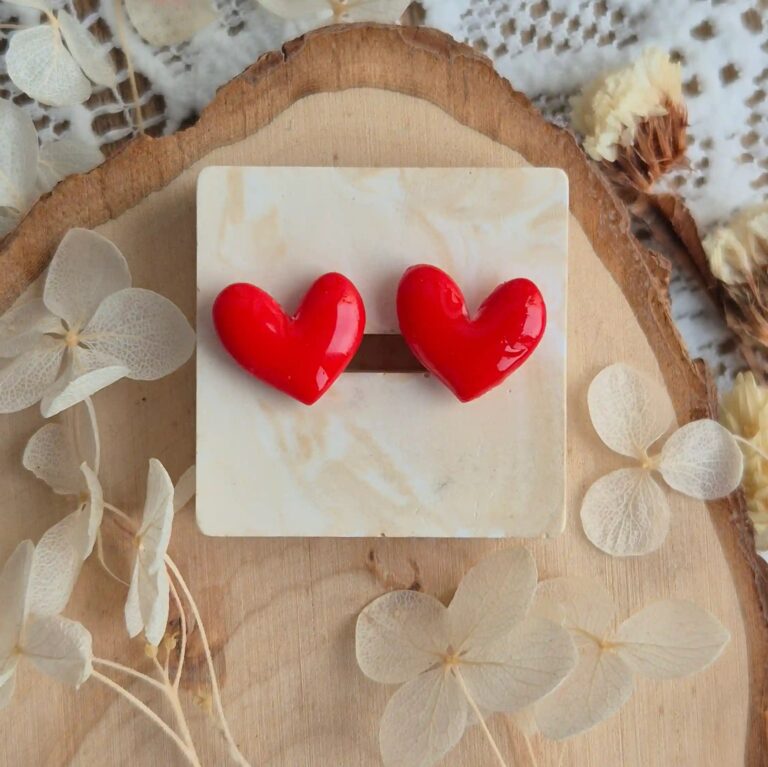 Cercei in forma de inimioara, de purtat pe lobul urechii. Cerceii sunt stralucitori, fiind acoperiti cu un strat de rasina biocompatibila. Asezarea in ureche se face prin intermediul unui platou din otel inoxidabil placat cu aur si fluturas din silicon. Se poate observa cum lumina se reflecta pe suprafata cerceilor. Bijuteria este asezata pe un suport patrat asemanator pietrei.