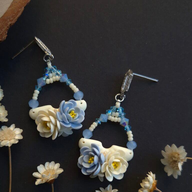 cercei din lut polimeric si cristale, in nuante de albastru si crem-vanilie fotografiate pe un fundal negru