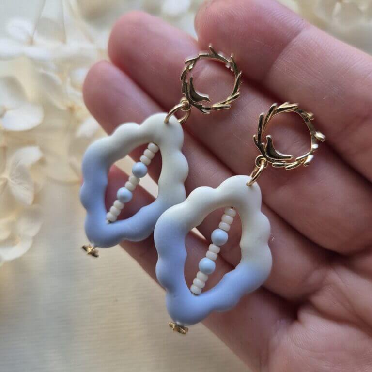 cercei din lut polimeric, in nunate albastru-vanilie in degradee, cu un rand de margele de sticla insirate dintr-un capat in altul al cerceilor. cerceii sunt tinuti in palma
