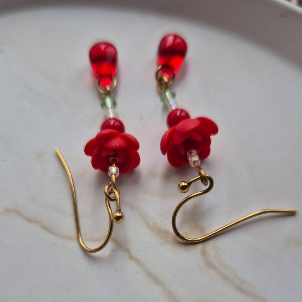 accent pe tortite otel inoxidabil placate cu aur, cerceii cu flori rosii si cristale se vad doar in fundal, usor blurati