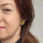 Femeie purtand o pereche de cercei lucrați manual în formă de plante suculente Echeveria, de culoare verde mentă cu detalii galbene pe marginea petalelor.